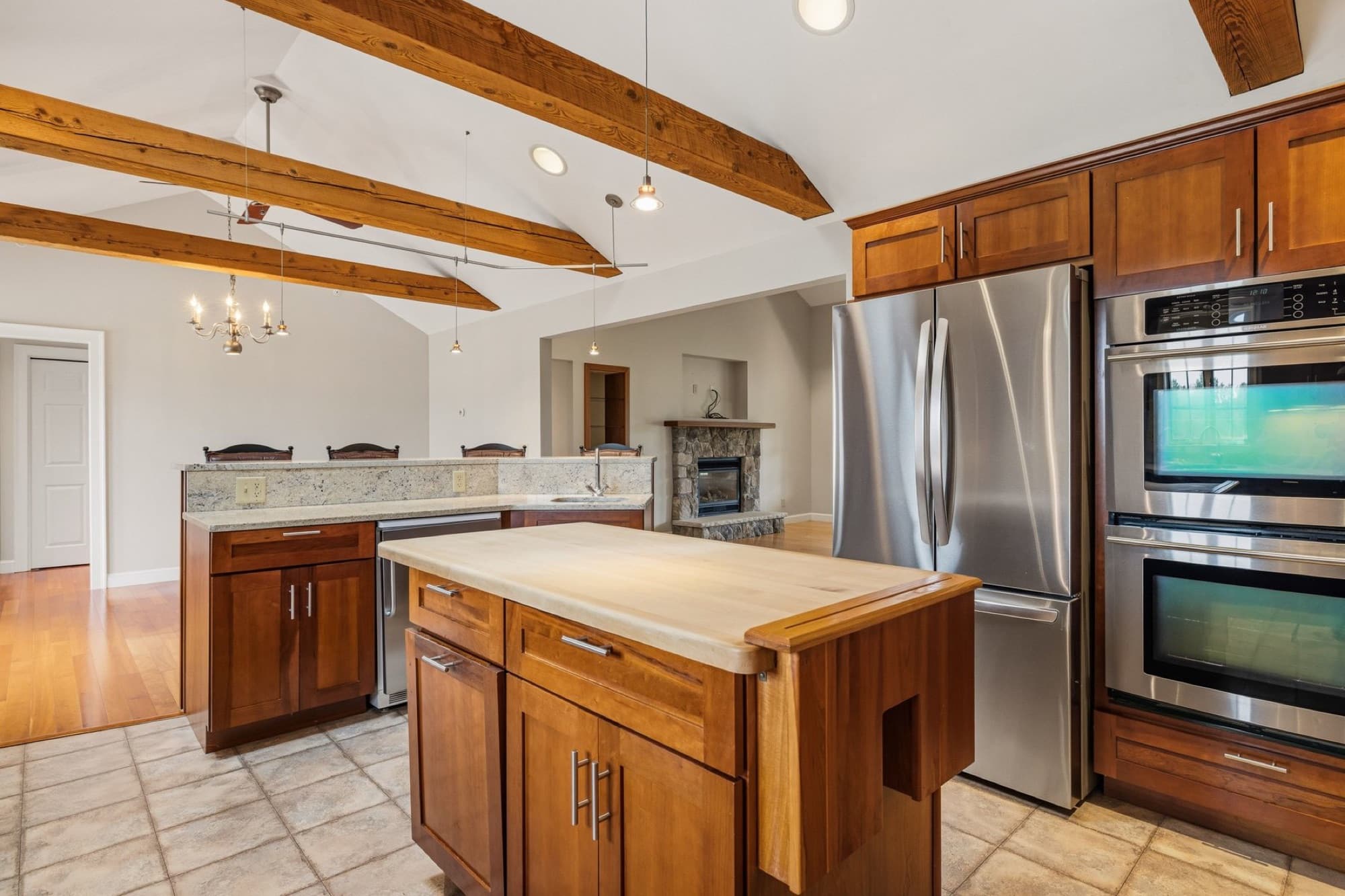 The kitchen with cherry cabinets, the refrigerator, the double wall ovens, and the island
