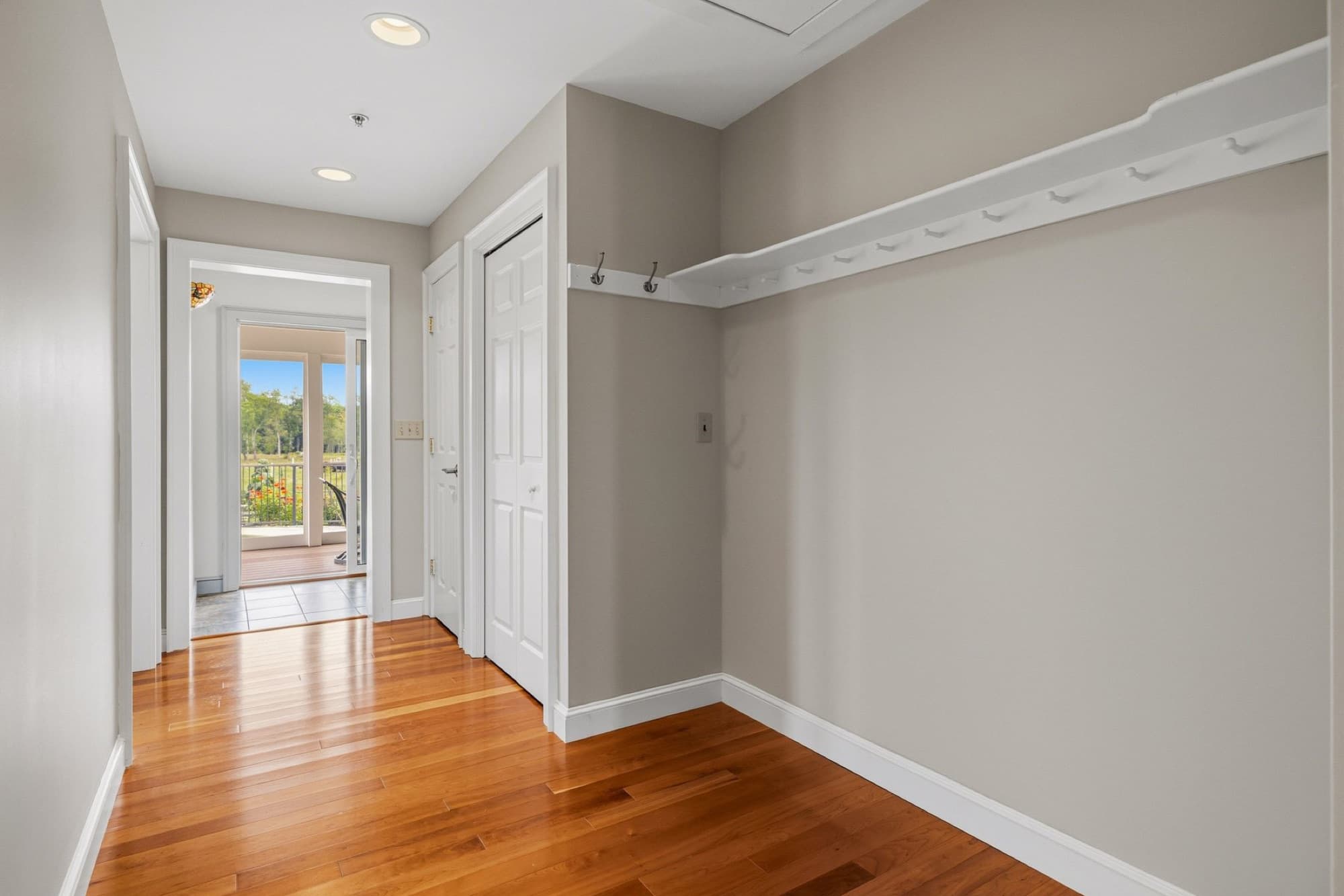 The mudroom with a row of coat hooks and the door to the screened porch